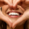 Close up of woman's mouth with hands making heart shape